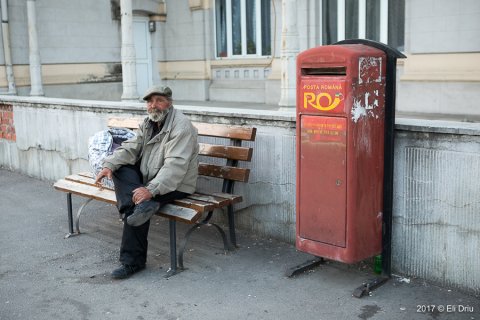 Un bărbat stă pe bancă și fumează o țigare în fața Gării Obor